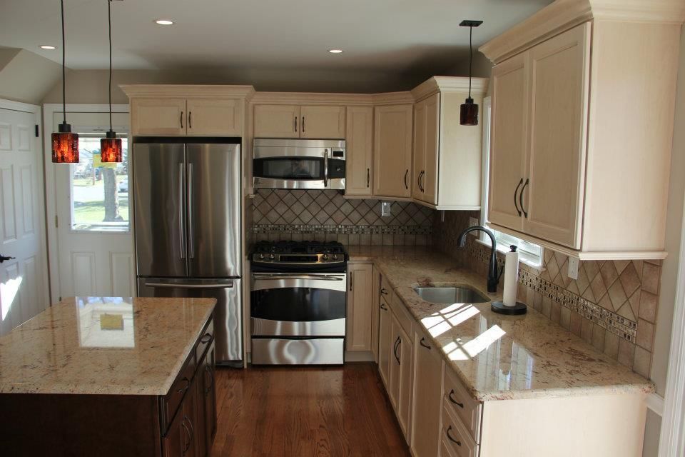 Cream-colored kitchen with stainless steel appliances, granite countertops, and dark brown island.