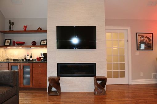 Living room with a fireplace, TV, bar, wooden stools, and glass-paneled door.
