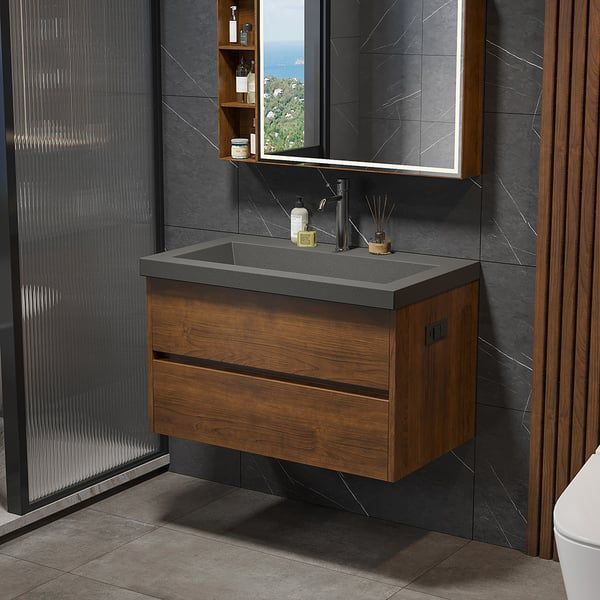 Wooden floating vanity with a dark countertop, mirror, and small cabinet in a modern bathroom.