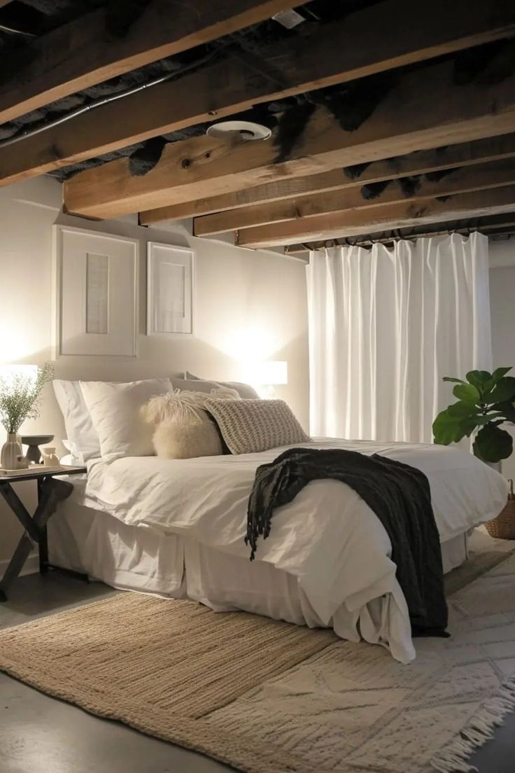 Bedroom with white bed, textured rug, exposed beams, and white curtains.