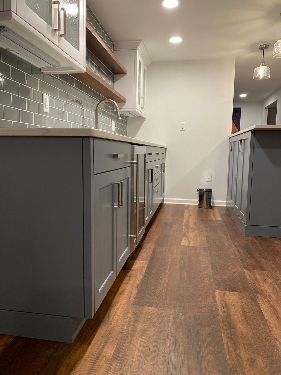 Modern kitchen with gray cabinets, subway tile backsplash, and wooden floors.