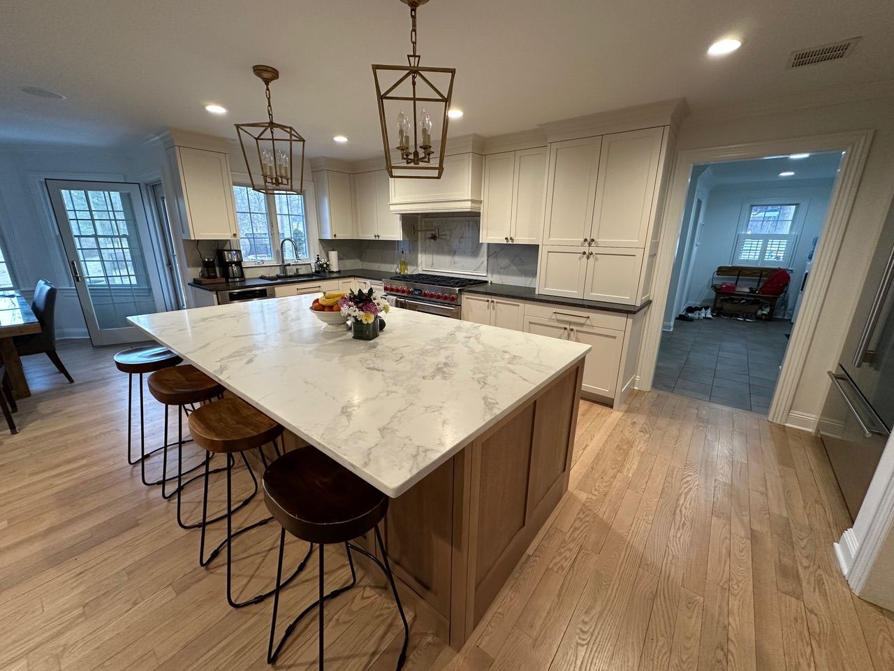 Spacious kitchen with a large island, wooden cabinets, and marble countertops, with overhead lanterns.