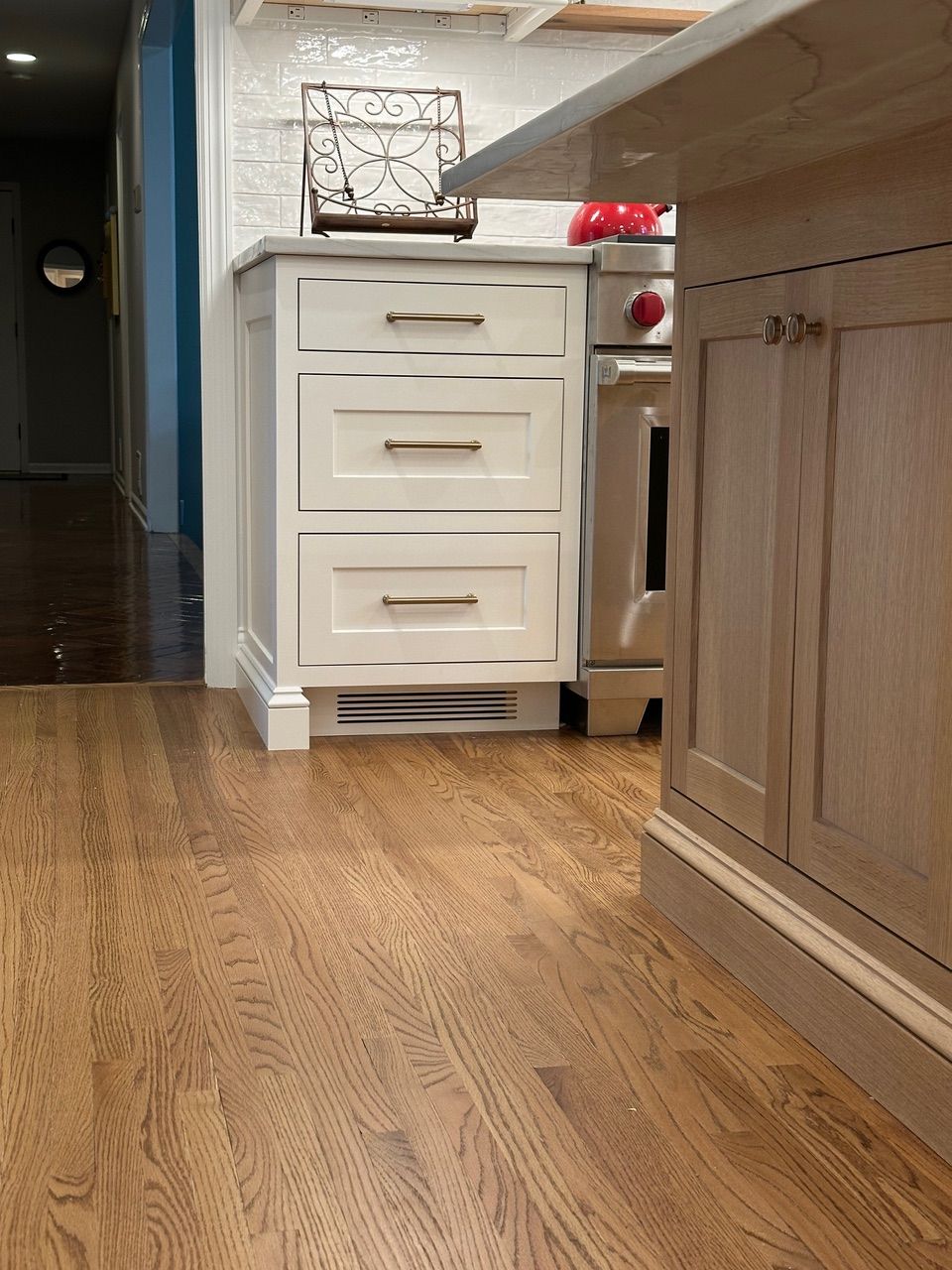 Wooden floor in a kitchen with white cabinets, a stove, and a countertop.