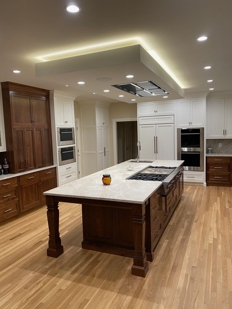 Luxurious kitchen with a large dark wood island, white cabinets, and light wood flooring.