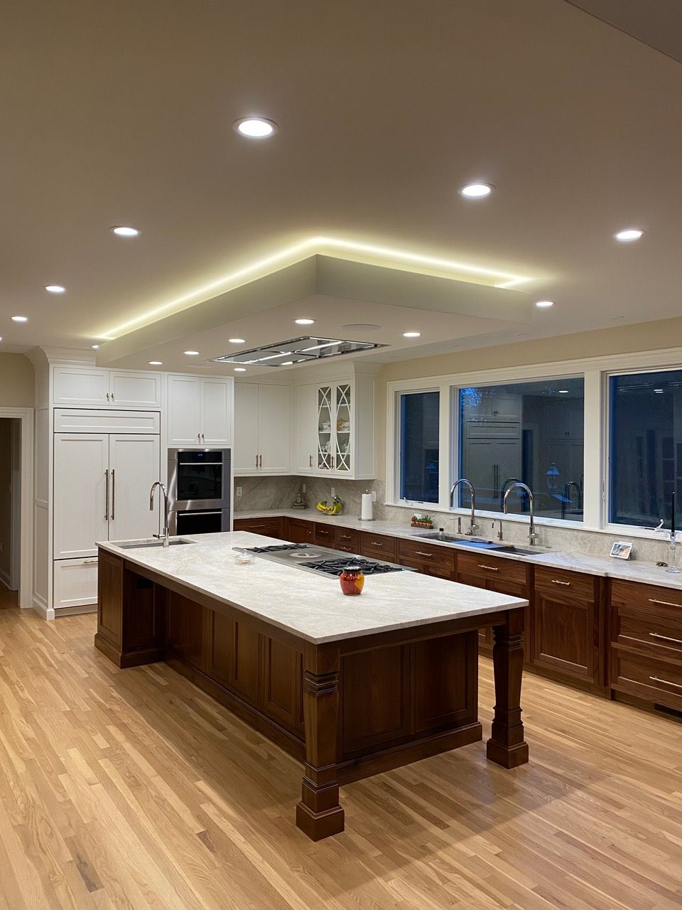 Kitchen with a large island, wood cabinets, and recessed lighting. A refrigerator and range are visible.