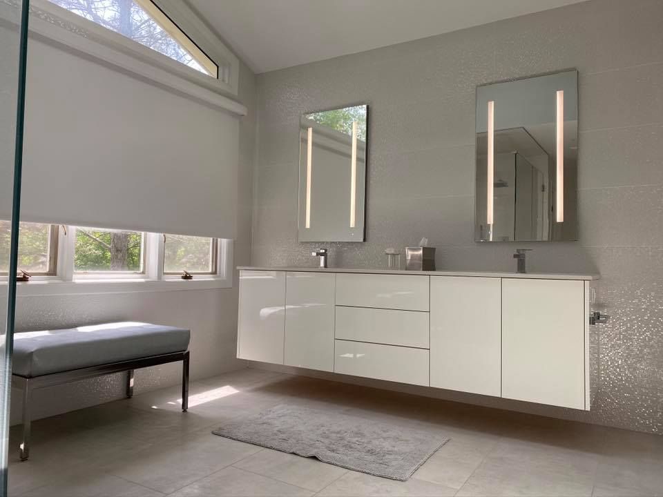Modern white bathroom with floating vanity, two mirrors, and a bench.