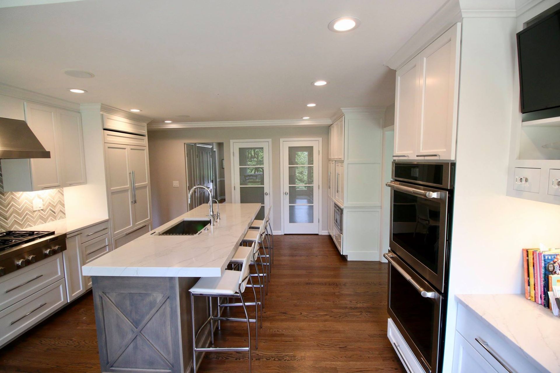 Kitchen with white cabinets, large island with seating, and stainless steel appliances.