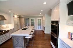 Modern kitchen with large island, white cabinets, stainless steel appliances, and wooden floor.