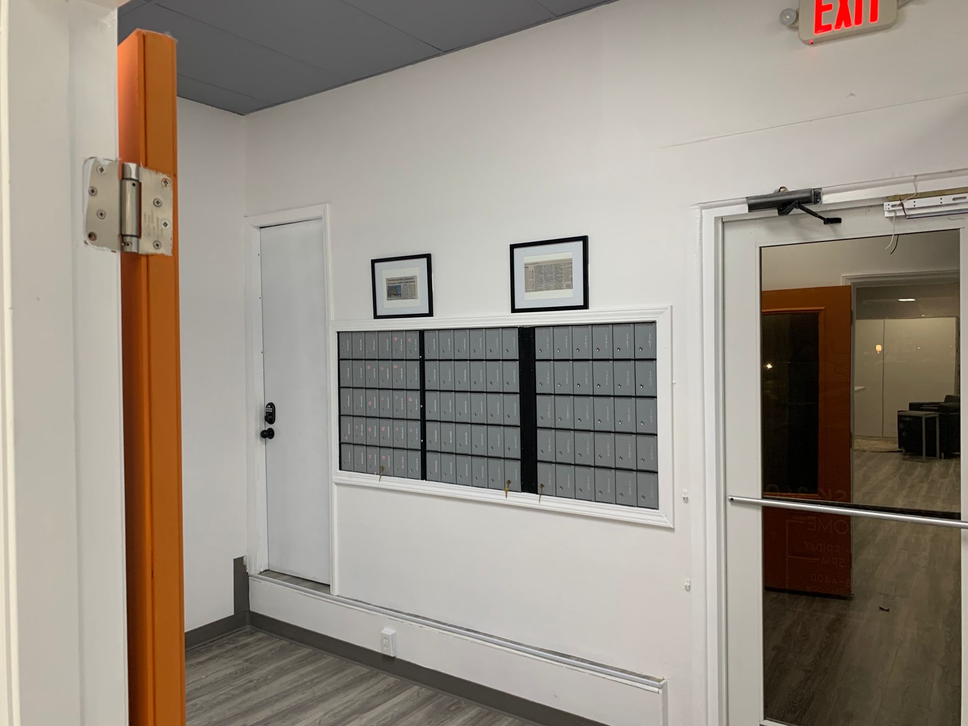 A hallway with a red exit sign on the wall.