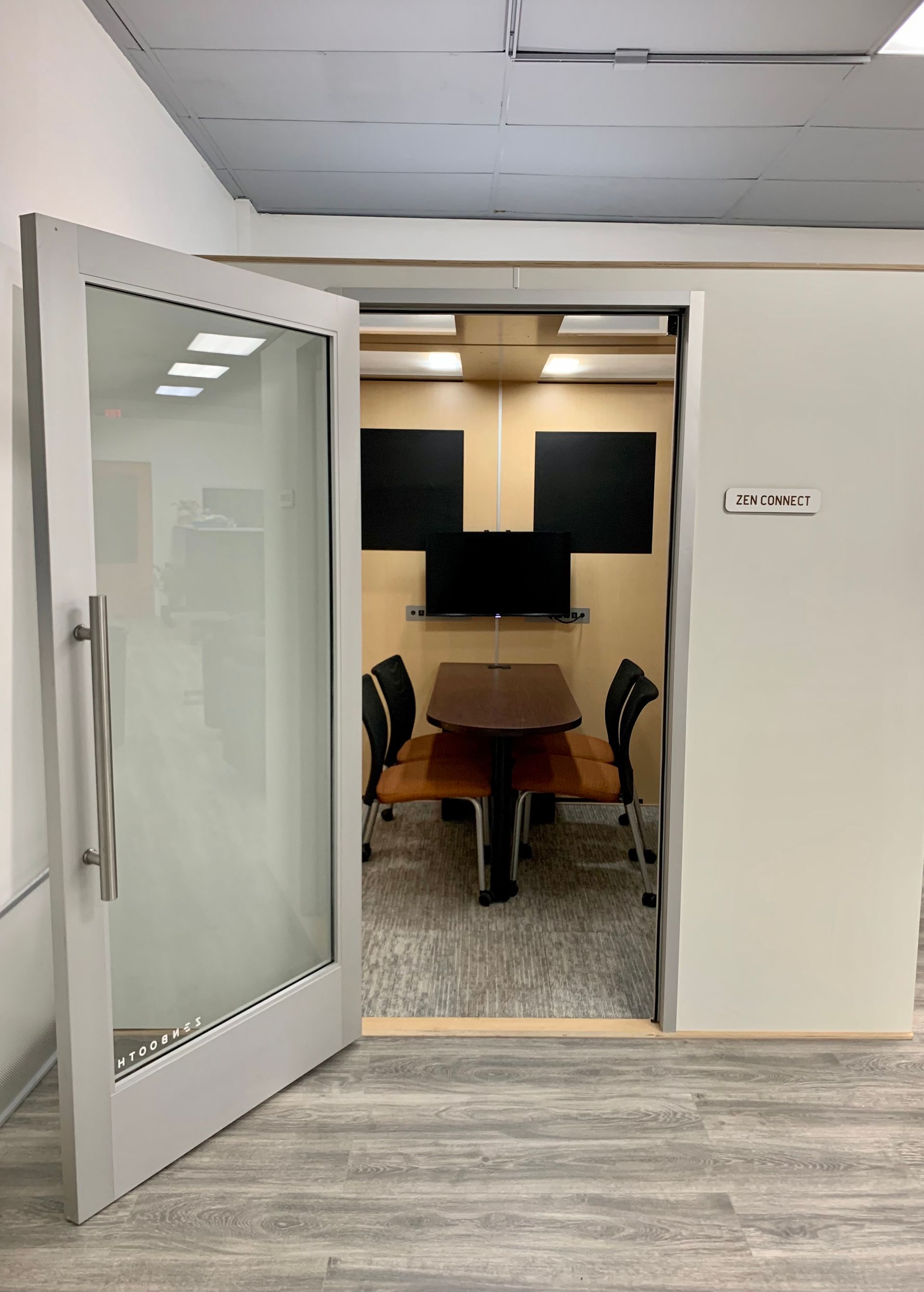 A conference room with a table and chairs and a door open.