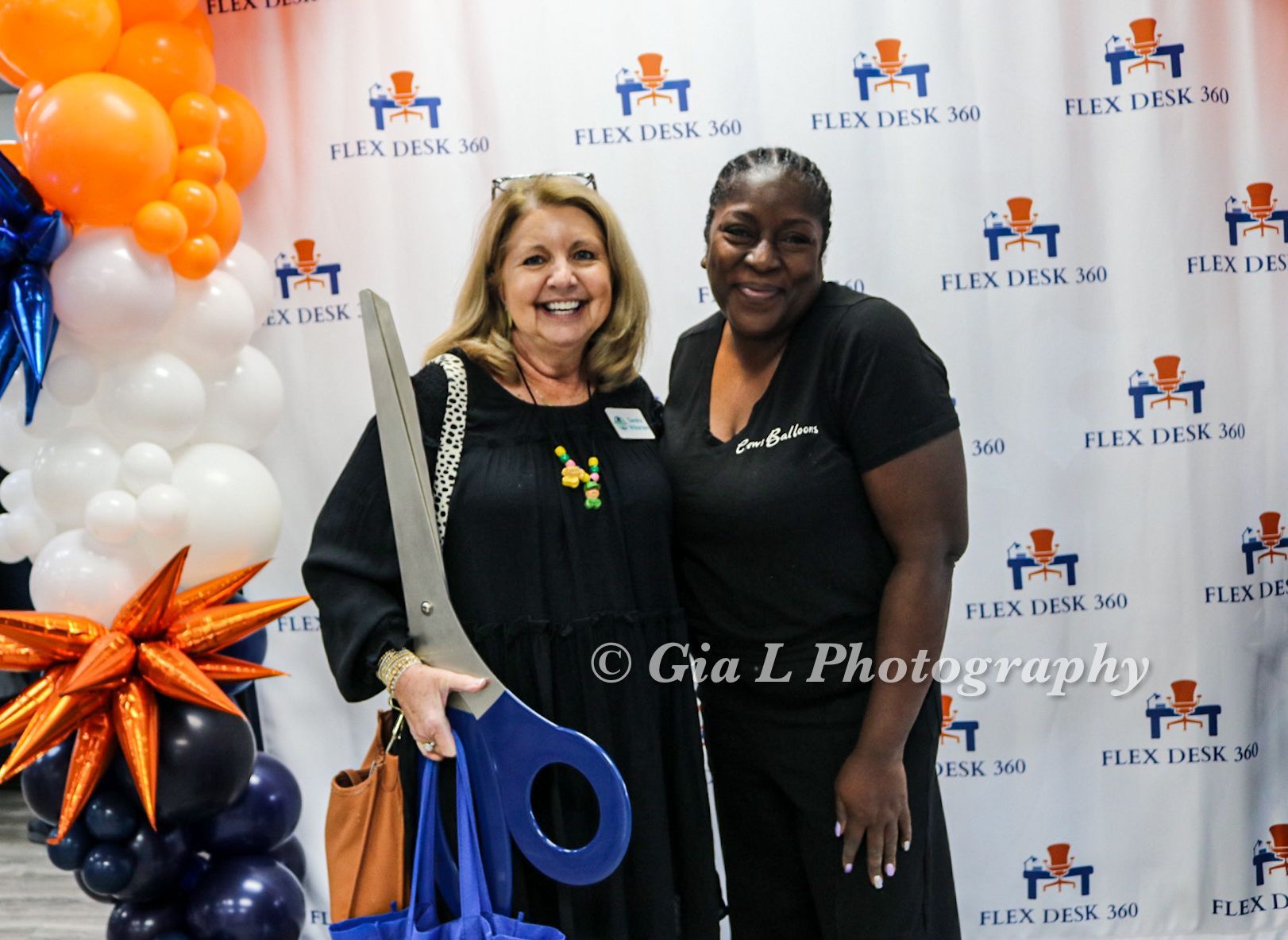 Two women standing next to each other in front of a flex desk sign