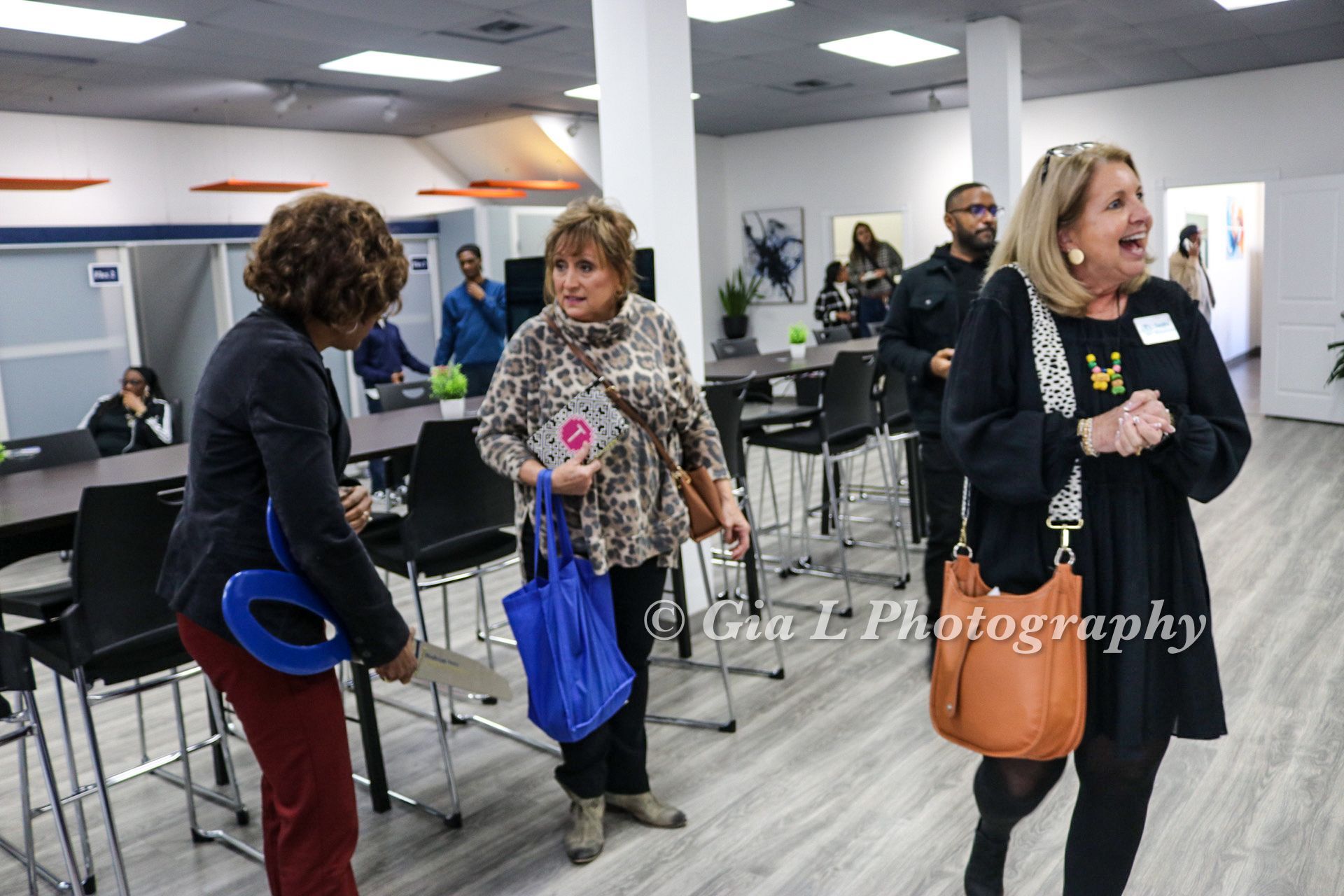 A group of women are standing in a room with tables and chairs.