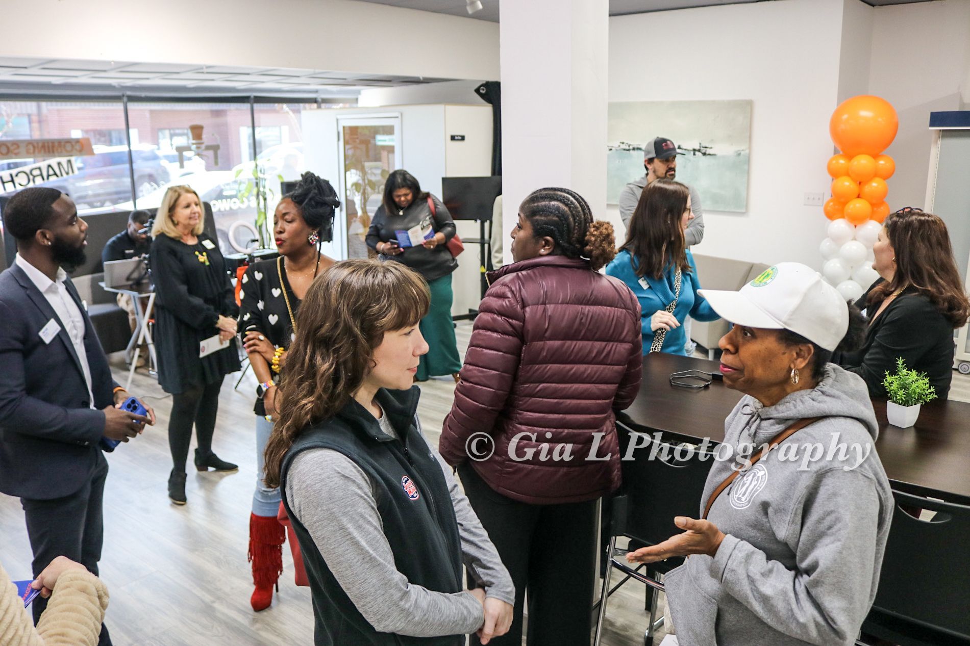 A group of people are standing in a room talking to each other.
