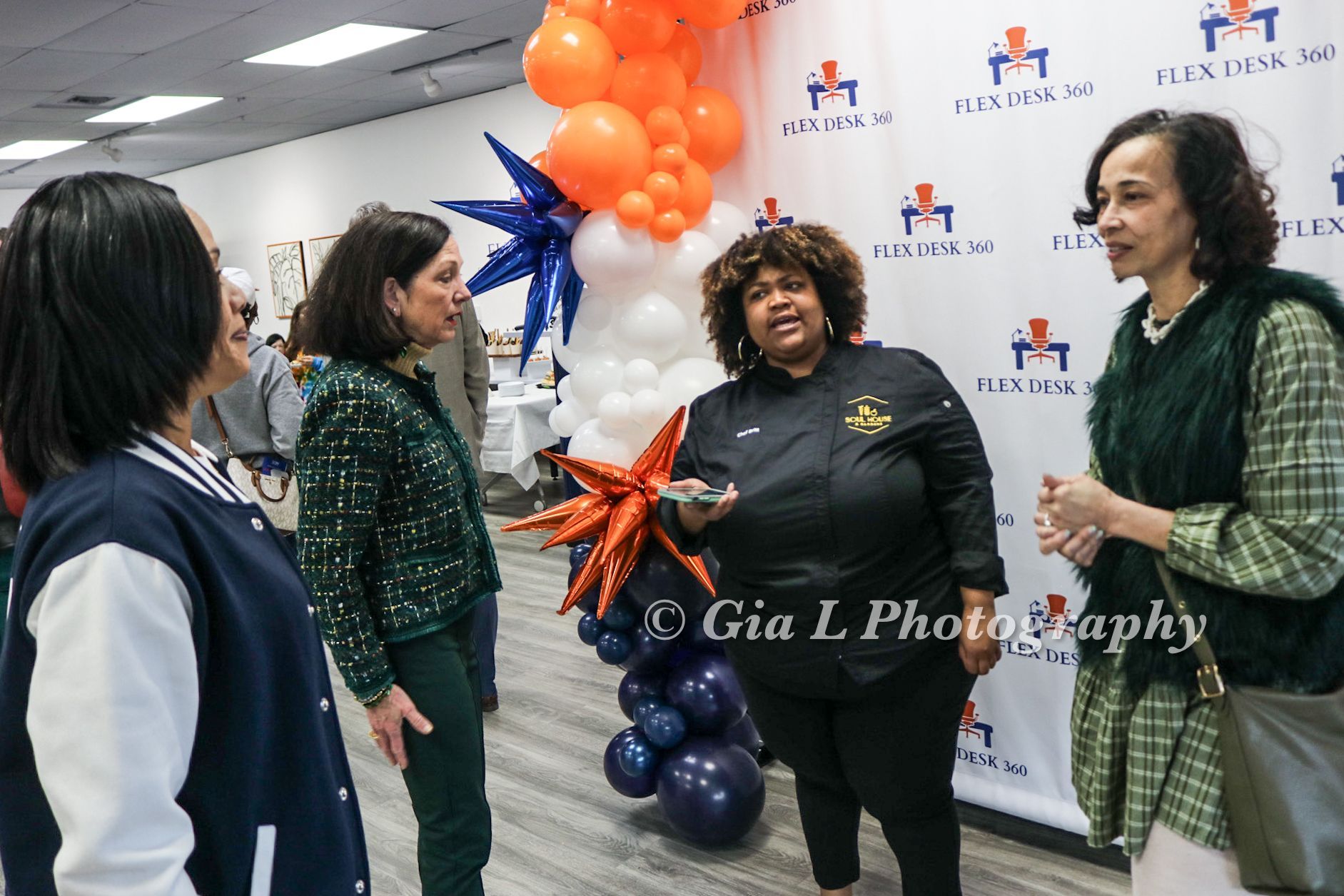 A group of women are standing next to each other in a room with balloons.