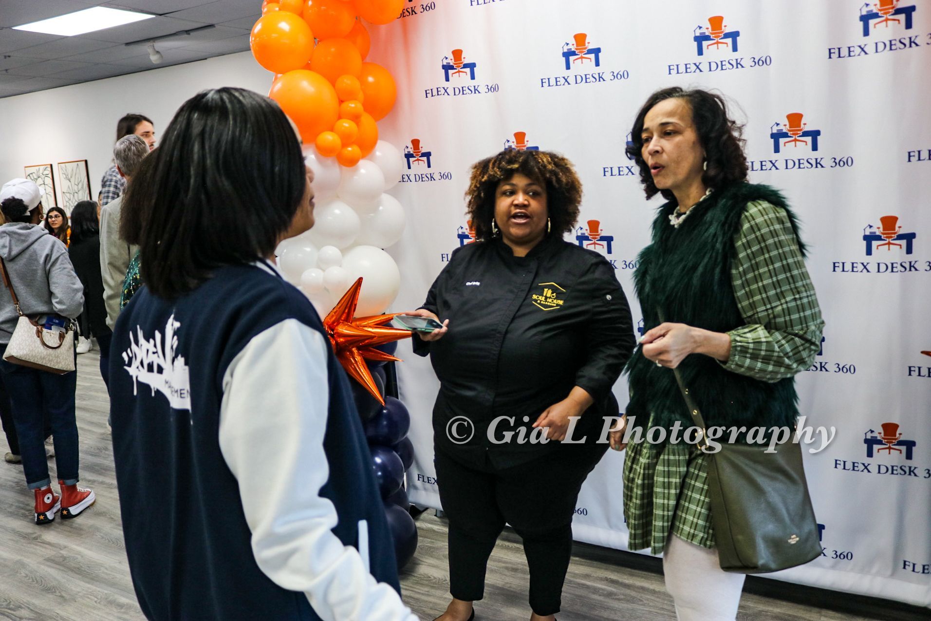 A group of women are standing next to each other in a room with balloons in the background.