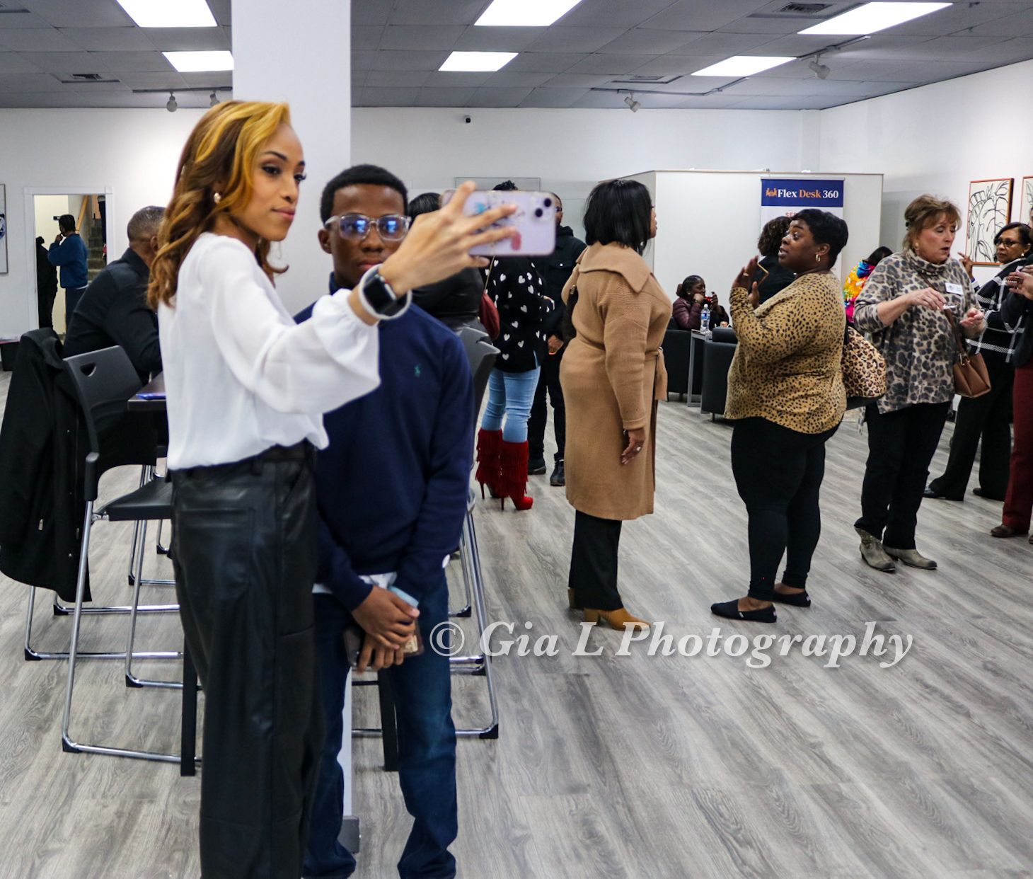 A woman taking a picture of a boy with a cell phone