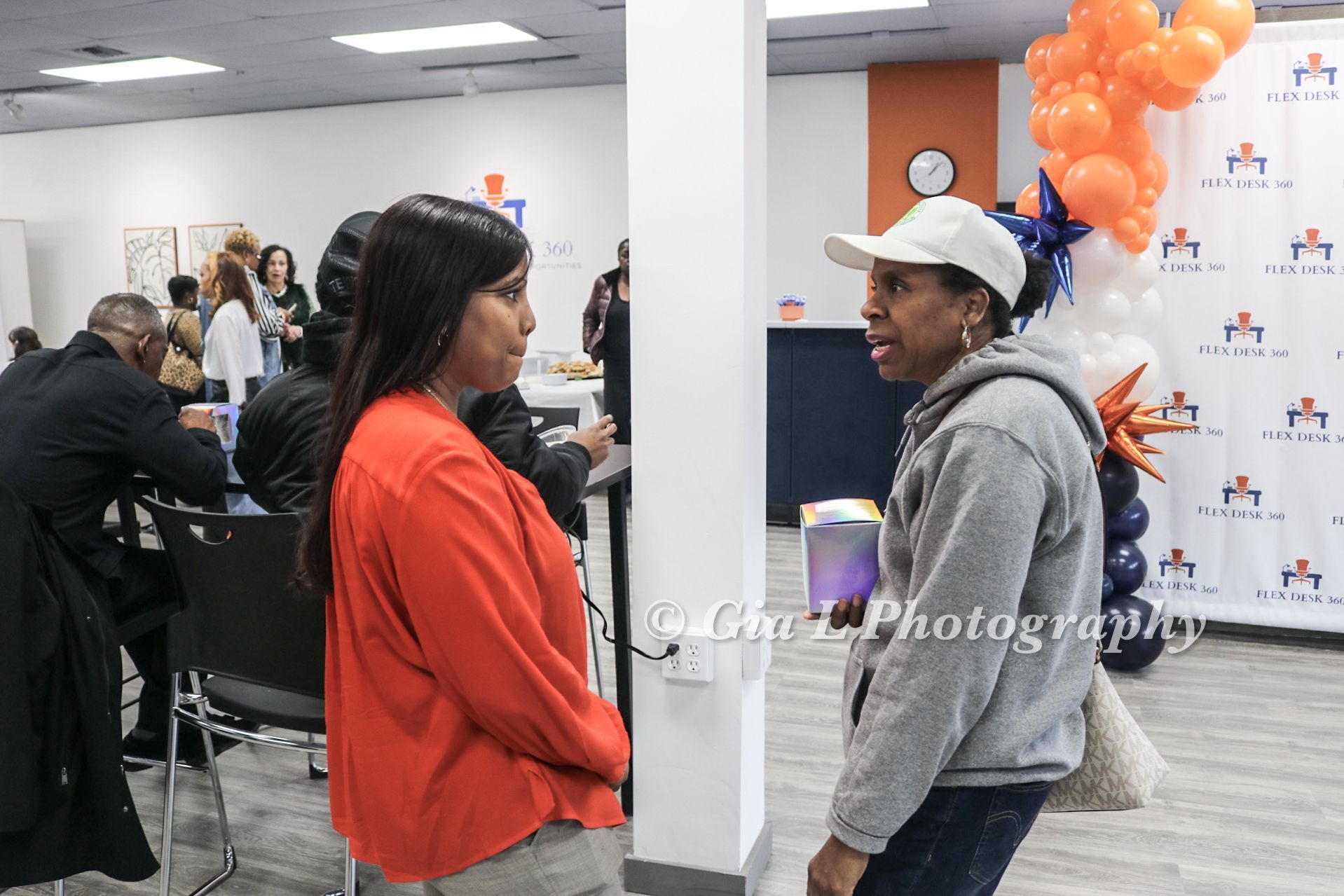 Two women are standing next to each other in a room with balloons.