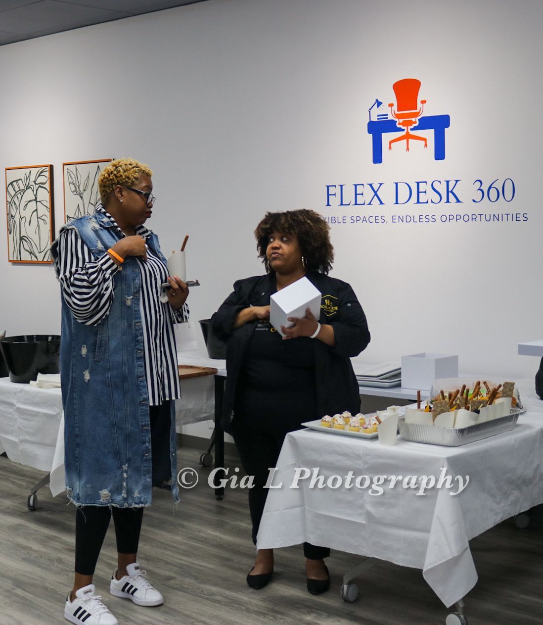 Two women standing in front of a flex desk 360 sign