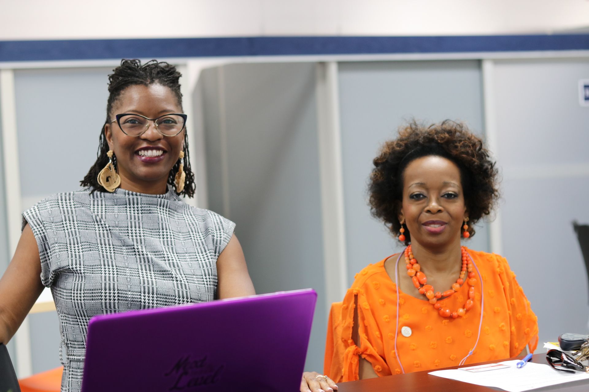 Two women are sitting at a table with a laptop.