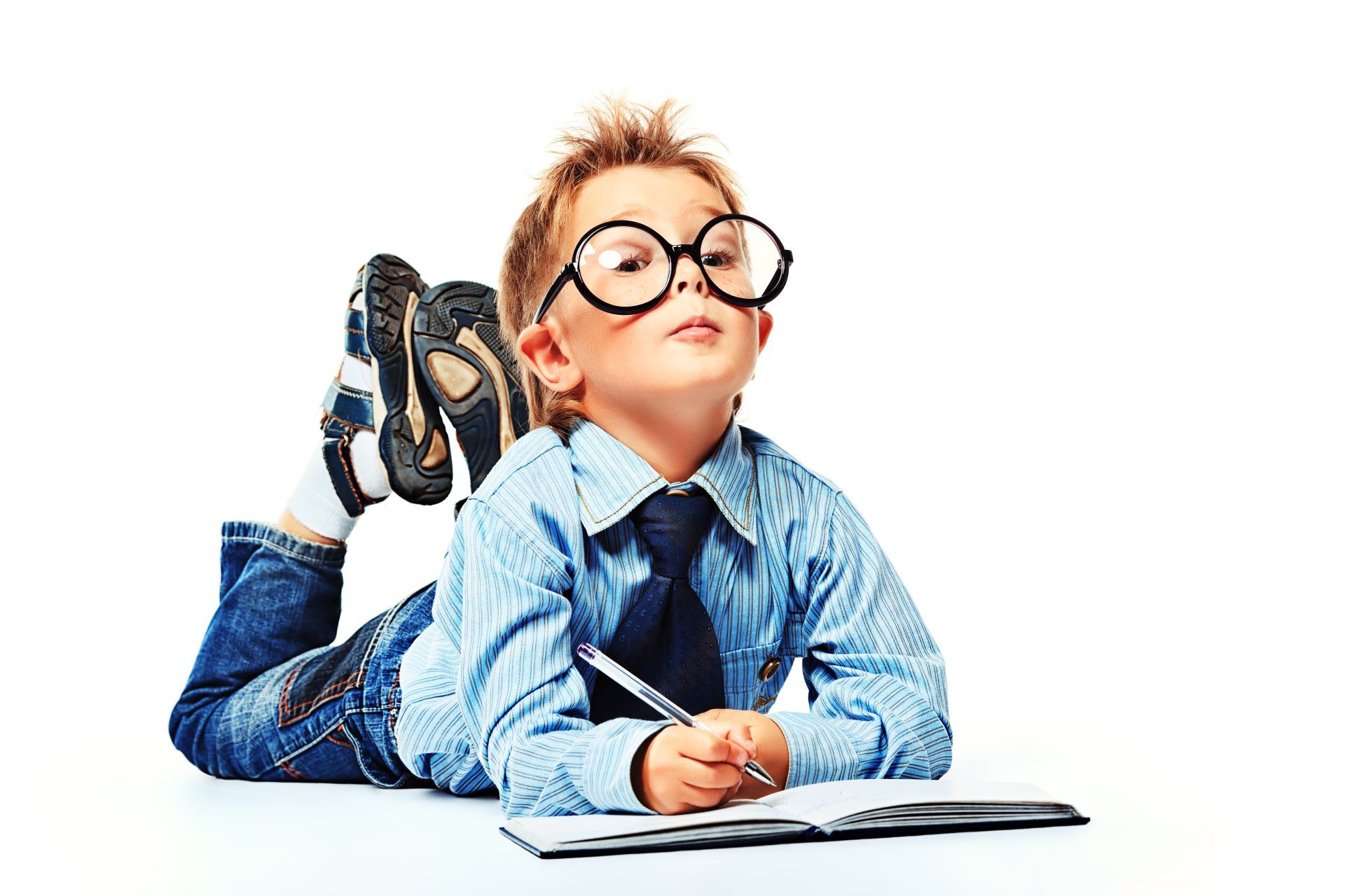 Little boy in spectacles and suit lying on a floor with a diary. Isolated over white background.