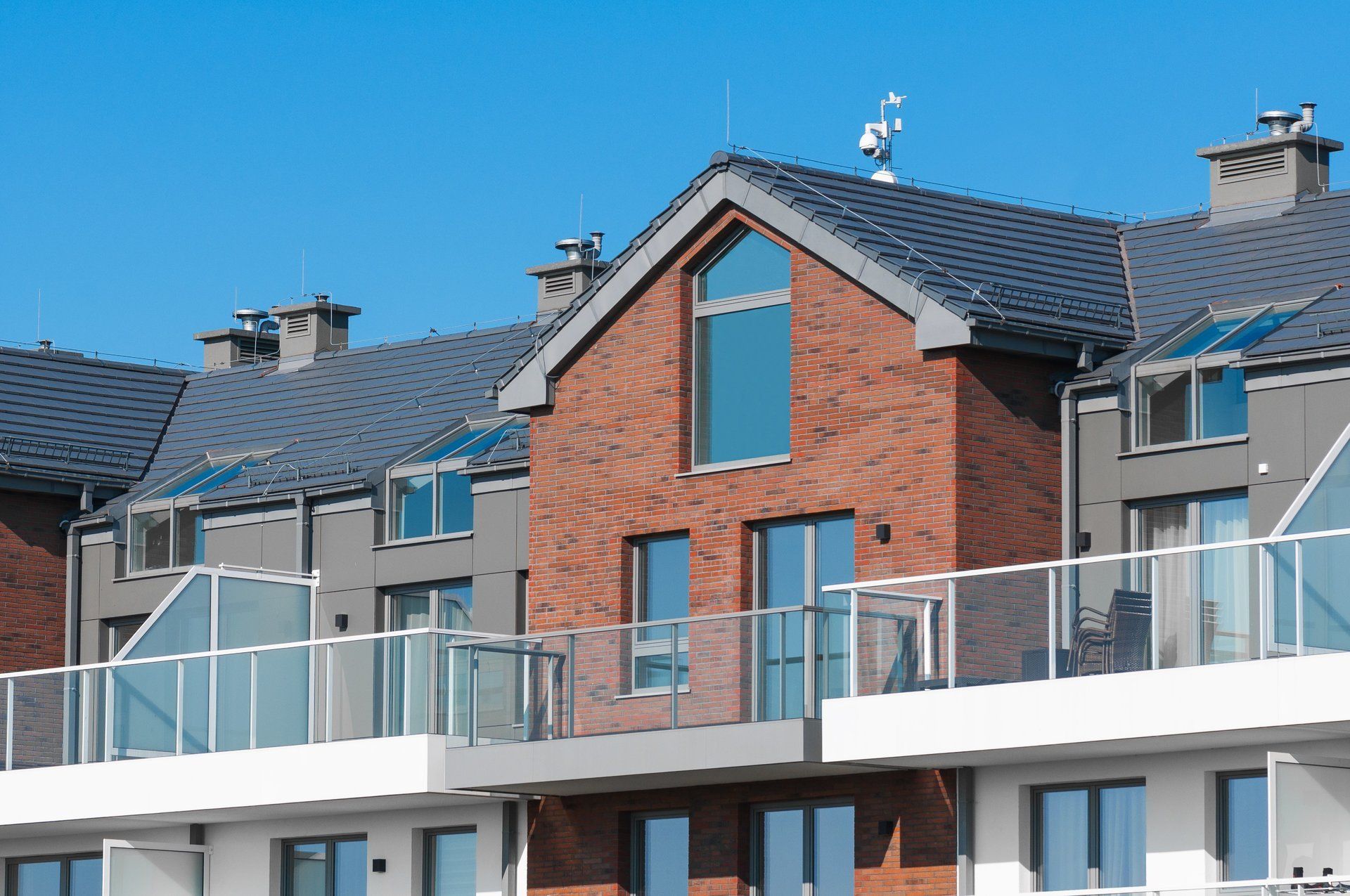 A row of houses with balconies and a blue sky in the background.