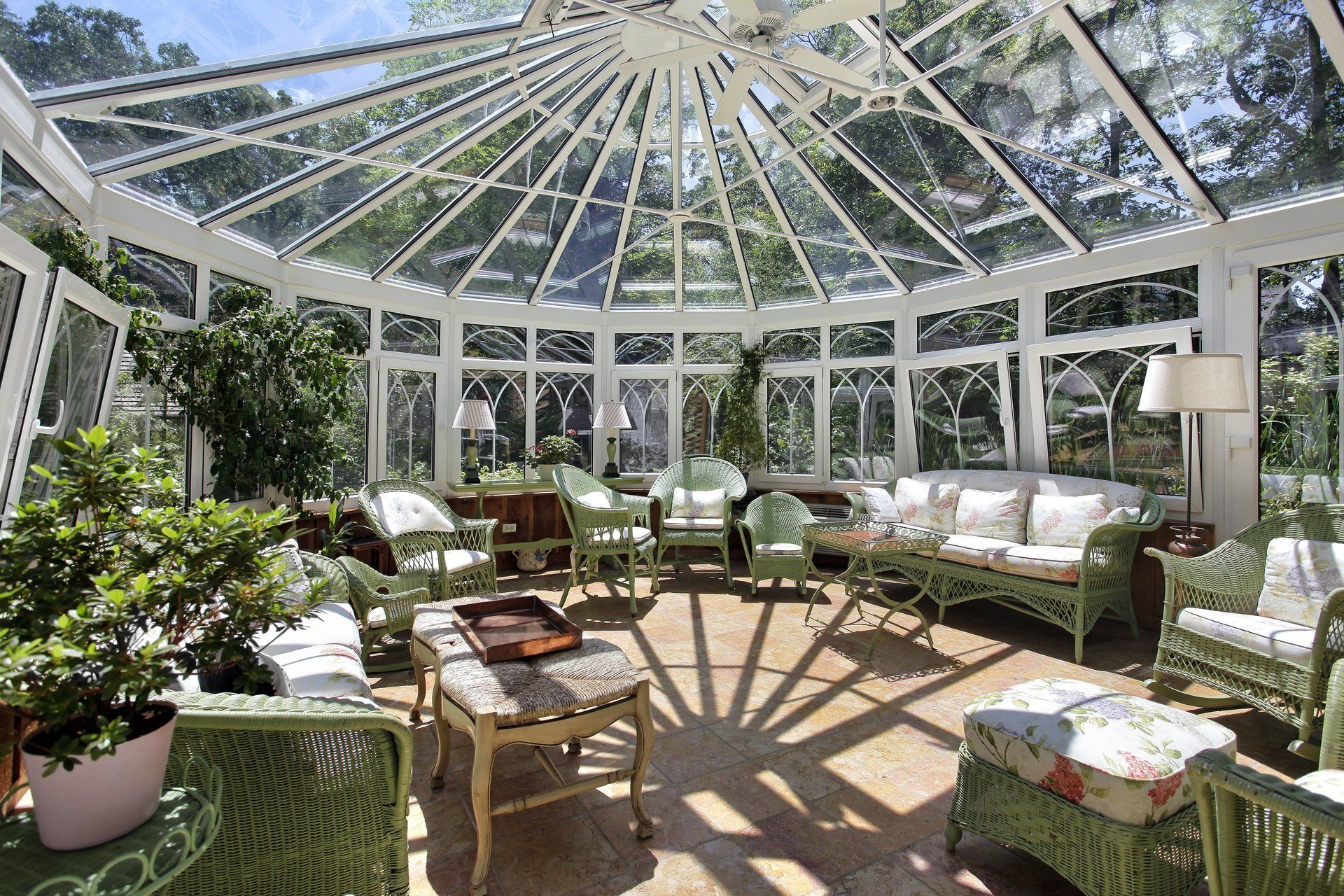 A large conservatory with wicker furniture and a glass roof.