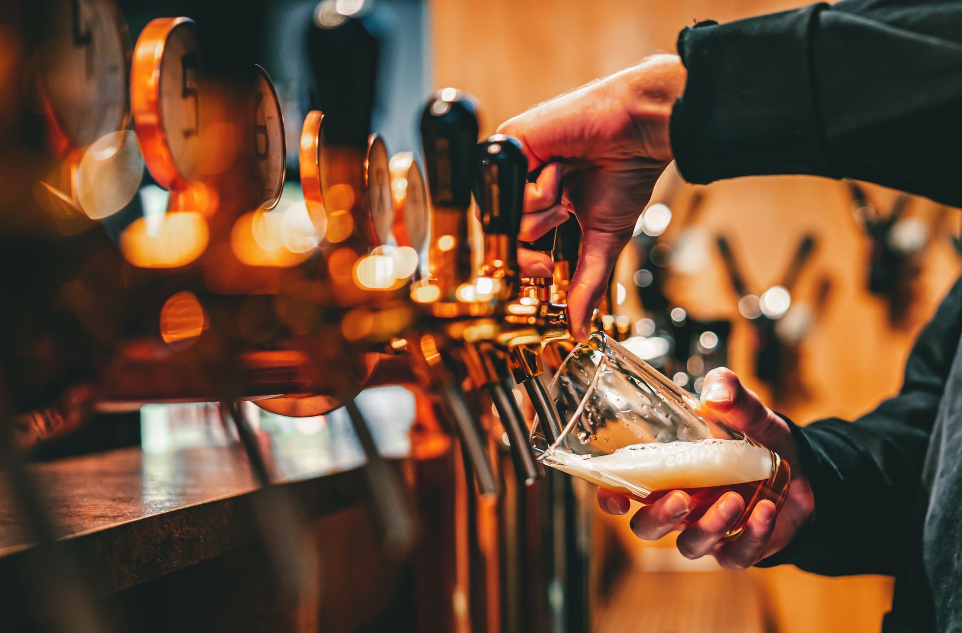 A person is pouring beer into a glass at a bar.