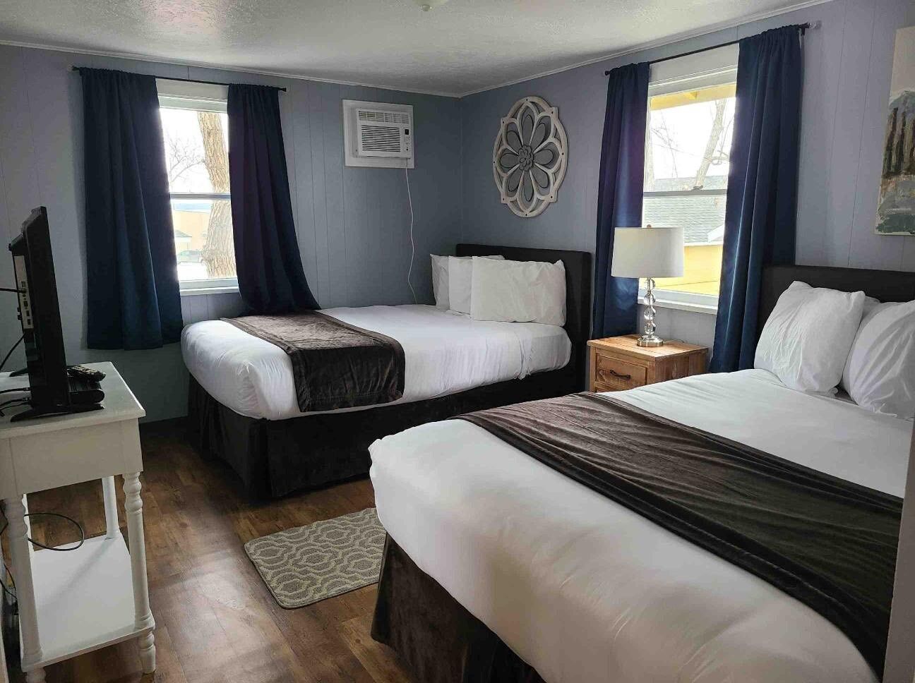 A hotel room with two beds and a television.