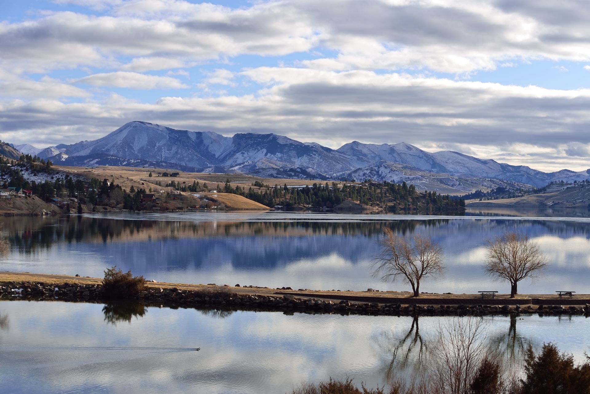 A lake with mountains in the background and trees on the shore