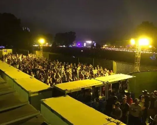 A large crowd of people are gathered on a stage at night for portable toilets by aeroflush sanitrax