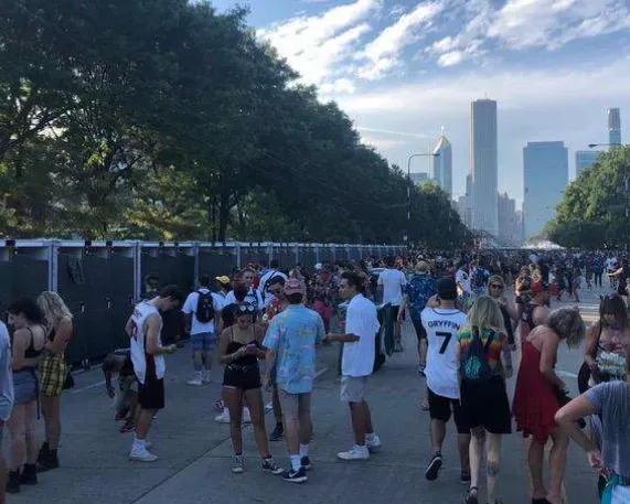 A crowd of people are in front of a city skyline. near sanitrax aeroflush portable toilets at a festival