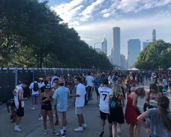 A crowd of people standing on in front of a city skyline. near sanitrax aeroflush portable toilets at a festival