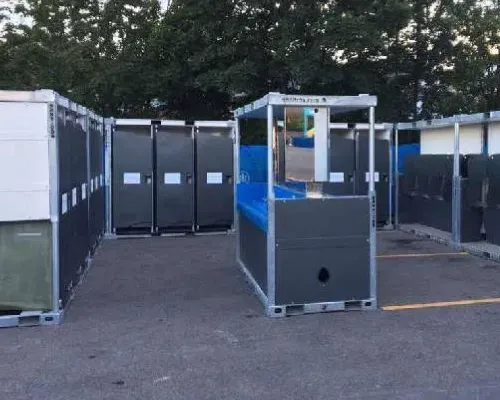 A row of portable aeroflush sanitrax toilets are lined up in a parking lot