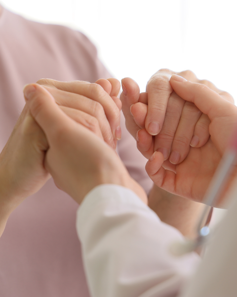 Two people holding hands in a close-up gesture of support