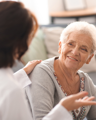 Smiling elderly woman receiving comfort from a caregiver indoors