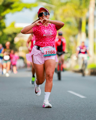 Runner in pink racing outfit covering face while running on a road during a race