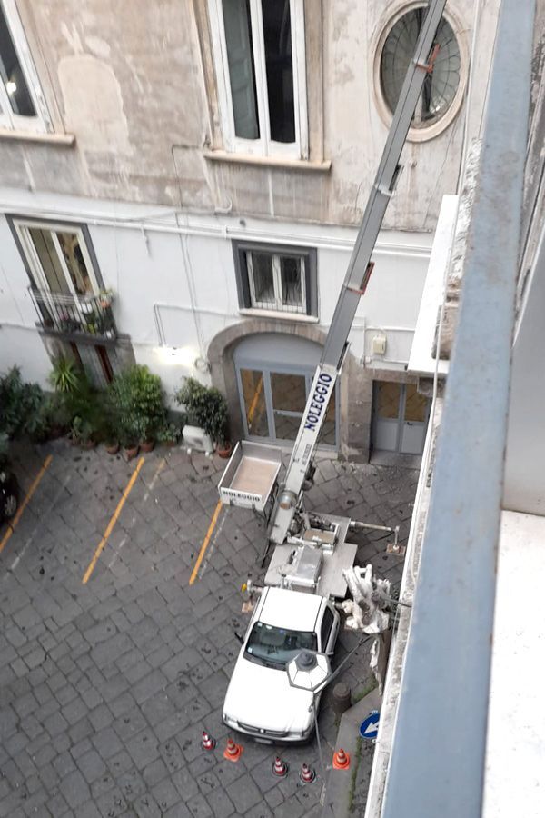 Un camion bianco con una gru sopra è parcheggiato davanti a un edificio.