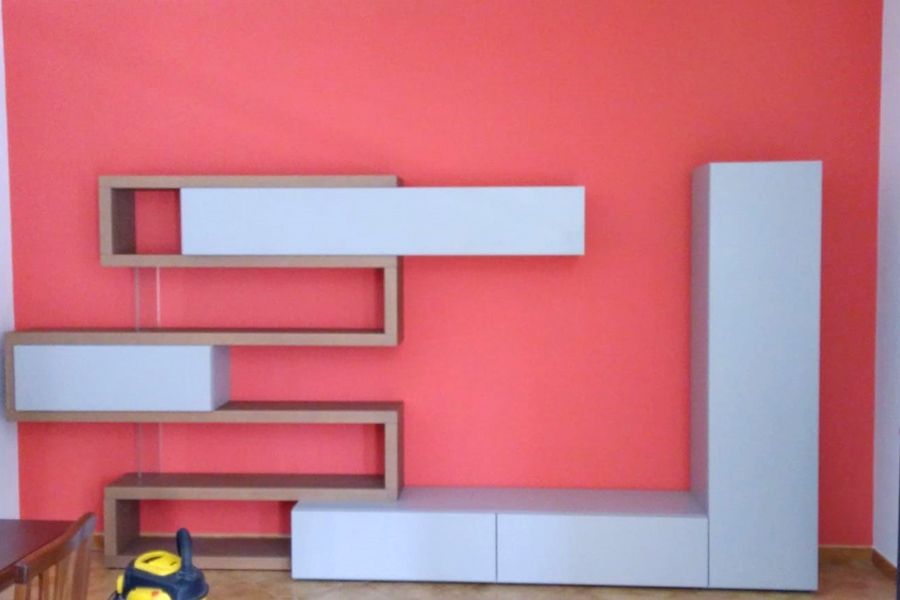 Un soggiorno con una parete rossa e scaffali bianchi