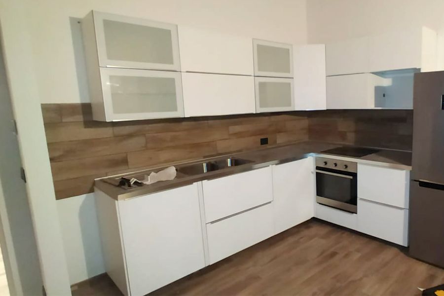 Una cucina con mobili bianchi ed elettrodomestici in acciaio inossidabile.