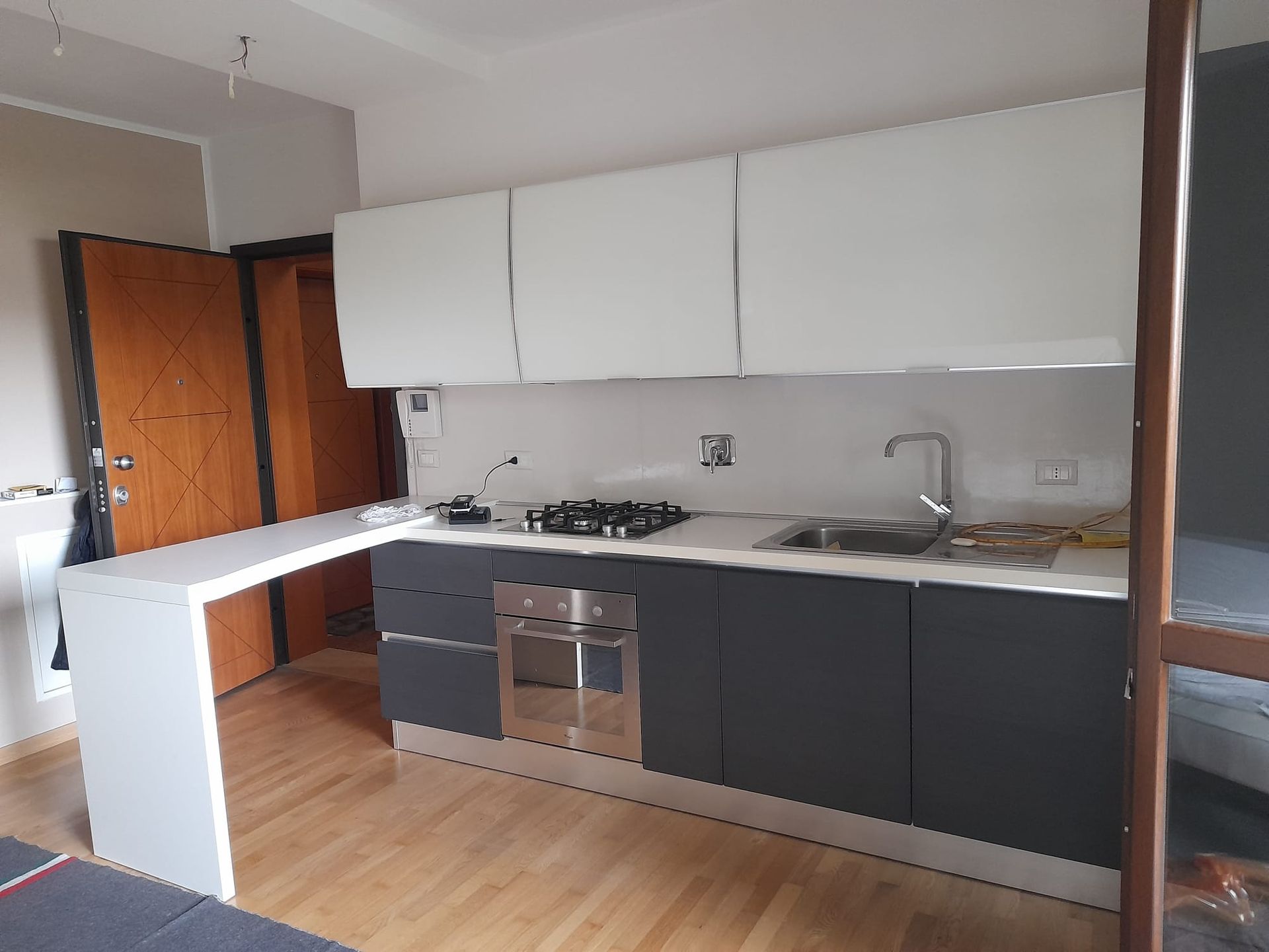 Una cucina con mobili grigi e ripiani bianchi