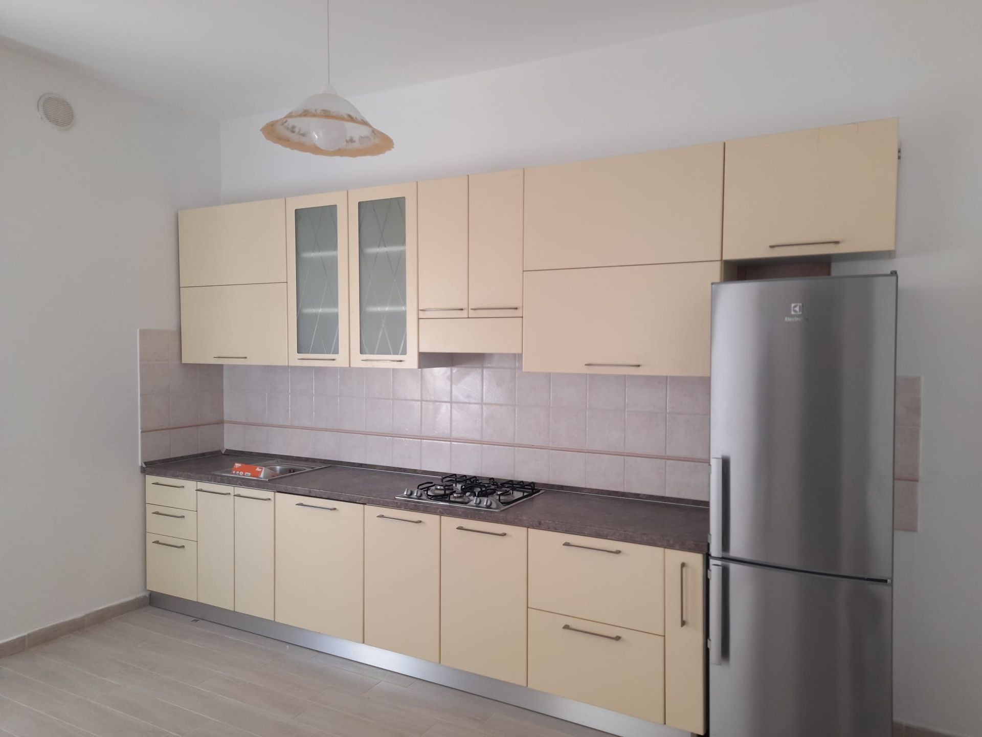 Una cucina con mobili bianchi e un frigorifero in acciaio inossidabile