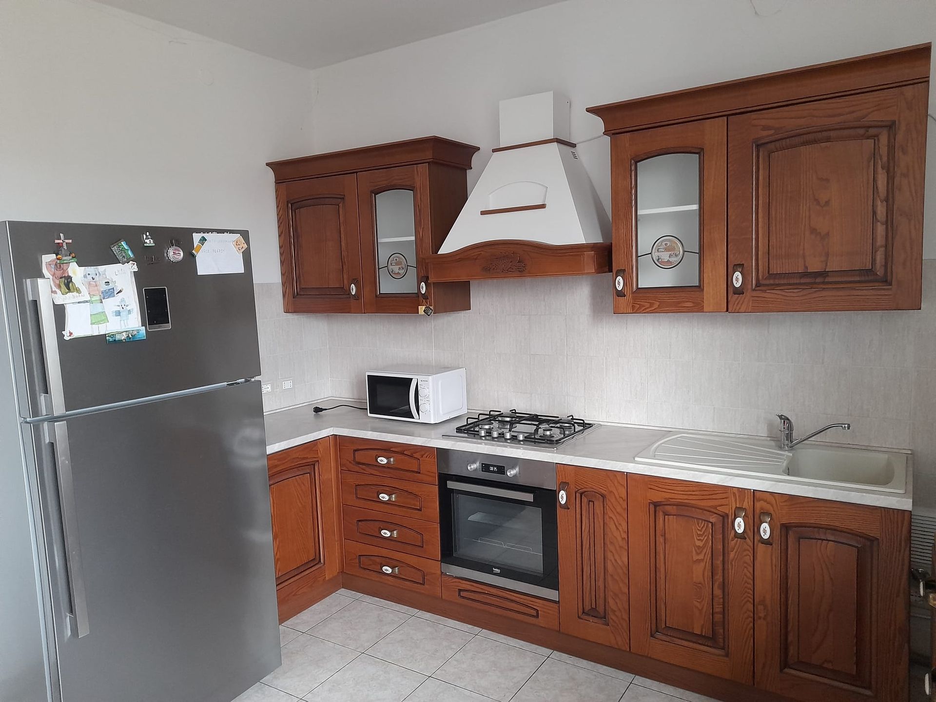 Una cucina con mobili in legno e un frigorifero in acciaio inossidabile