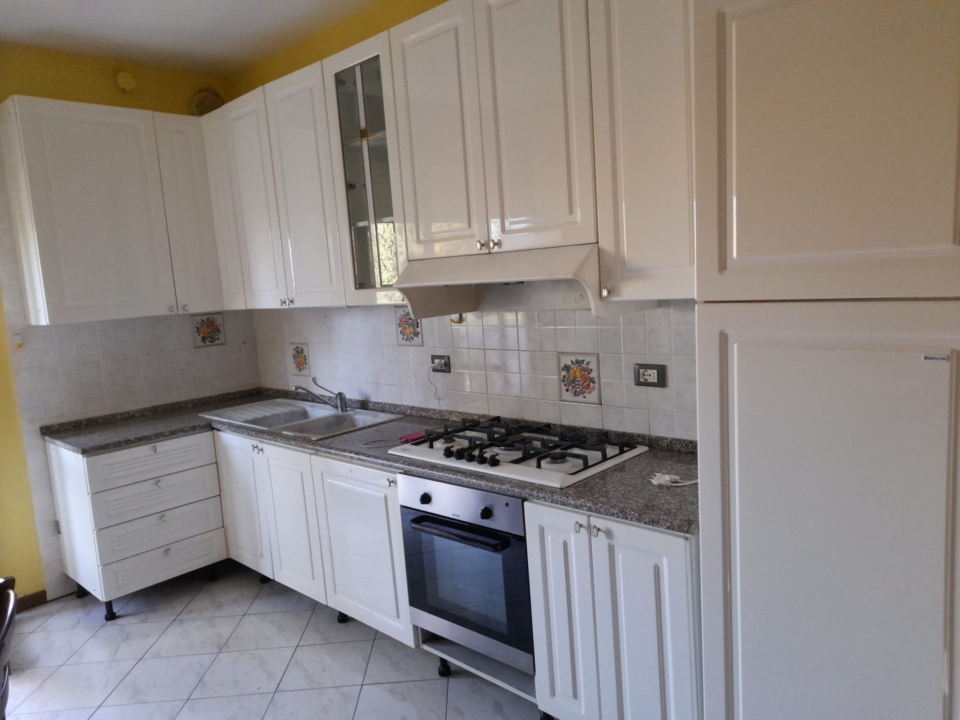 Una cucina con mobili bianchi e un forno con fornelli.