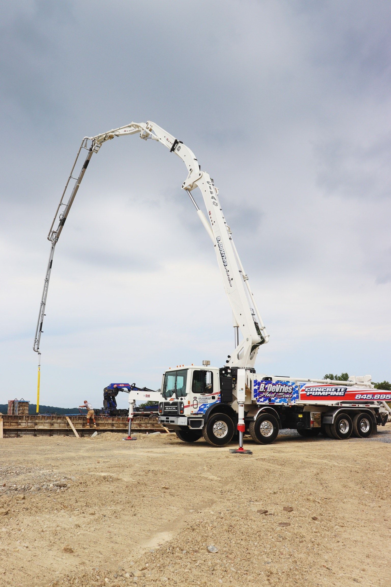 A concrete pump truck is pumping concrete in a dirt field.