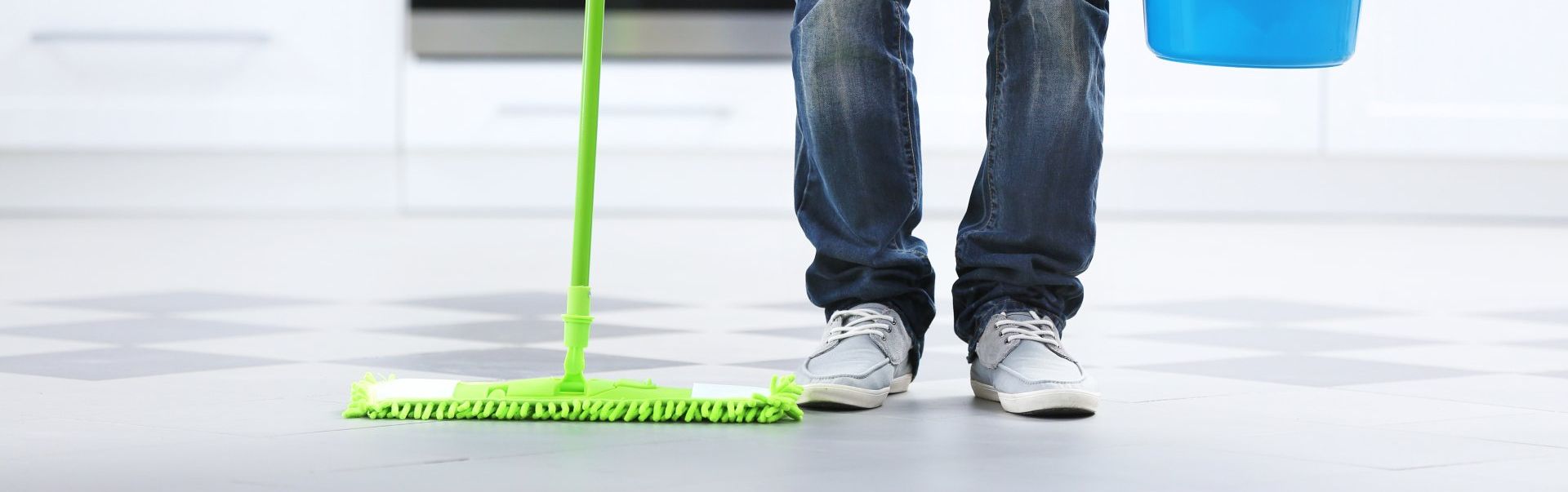 Un homme nettoie le sol avec une serpillière et un seau.