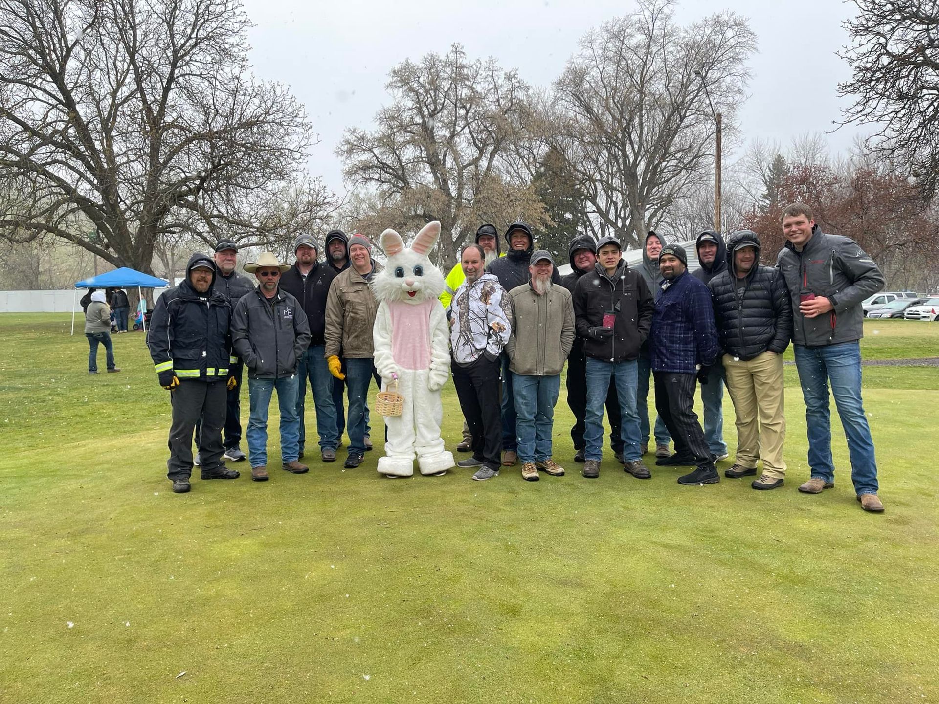 A group of men poses with the Easter Bunny on a grassy field