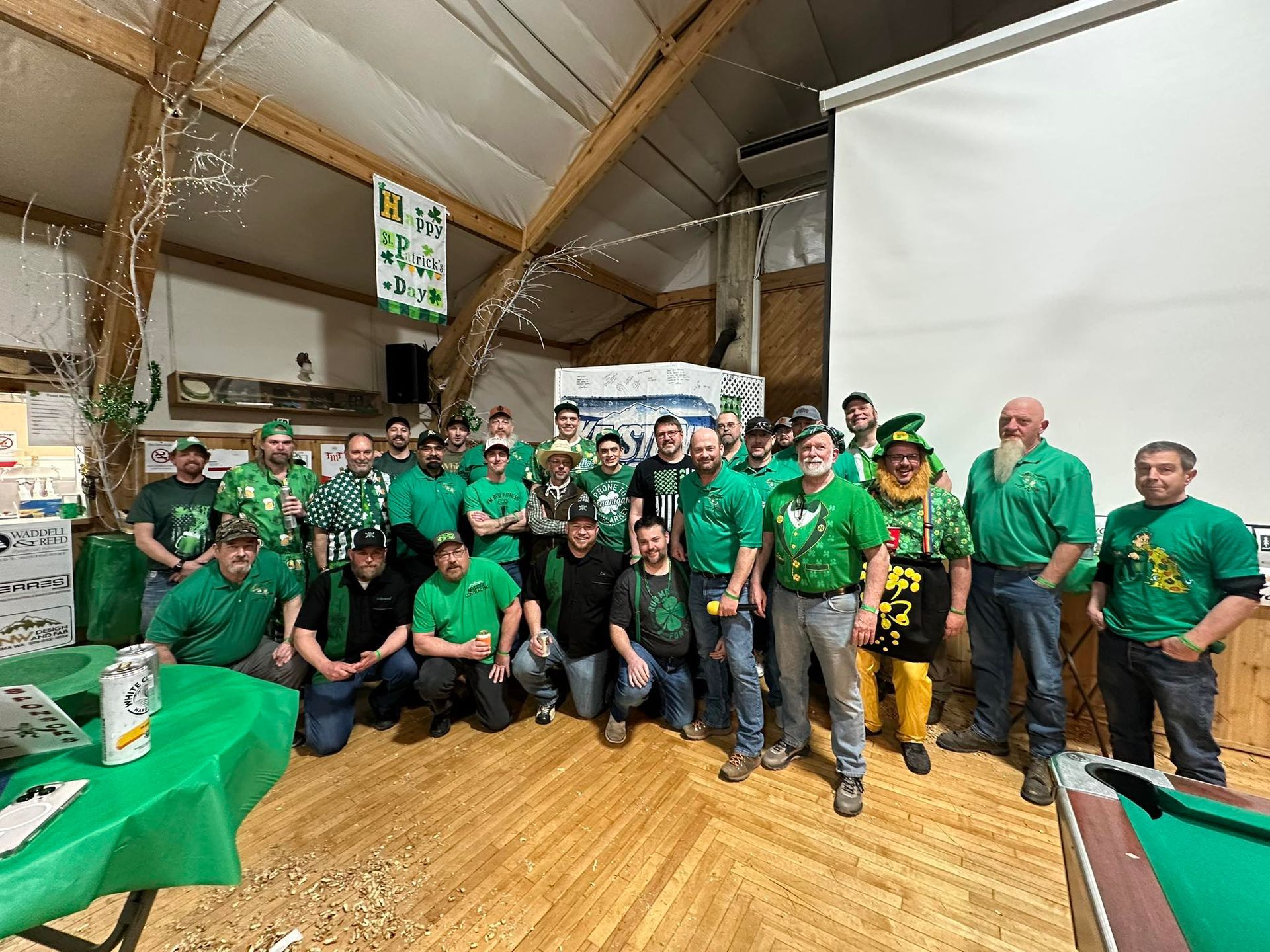 Group of men in green clothing celebrating St. Patrick's Day inside a venue with decorations.
