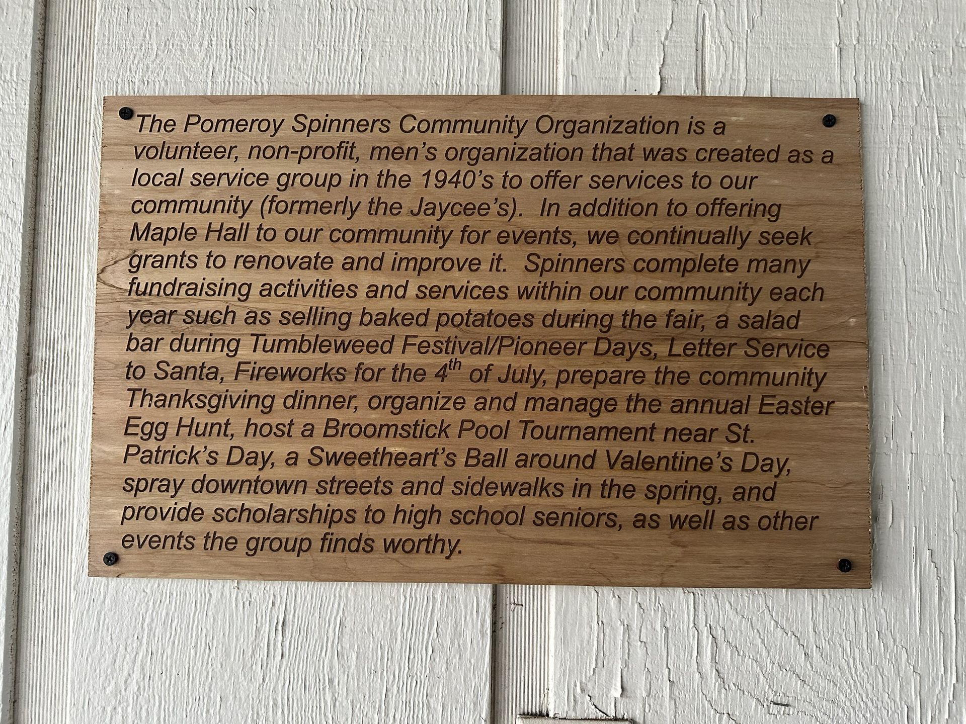 Wooden plaque on a white wall. Text details the Pomeroy Salines Community Organization's activities.