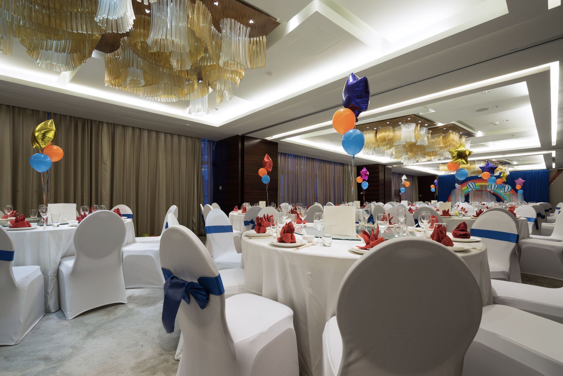 A banquet hall set for a celebration with round tables covered in white