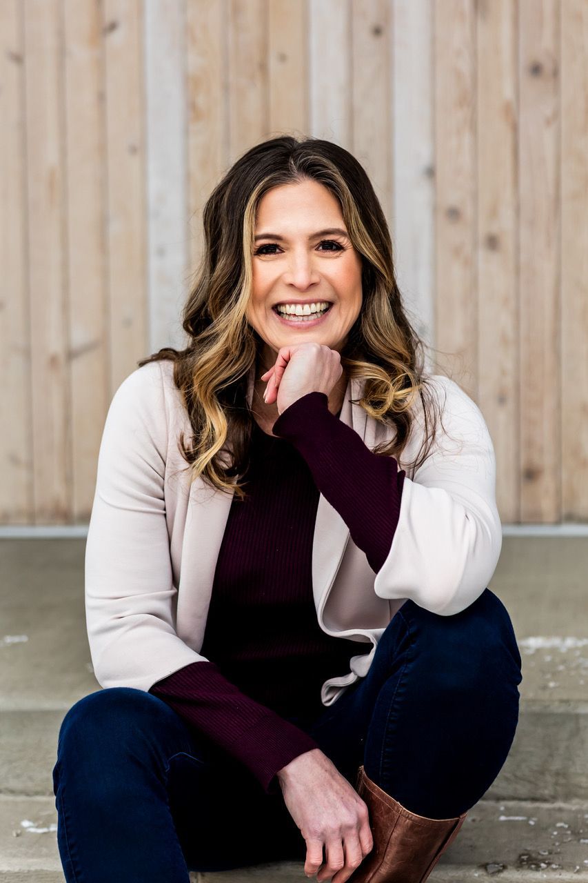 a woman is sitting on the ground with her legs crossed and smiling .
